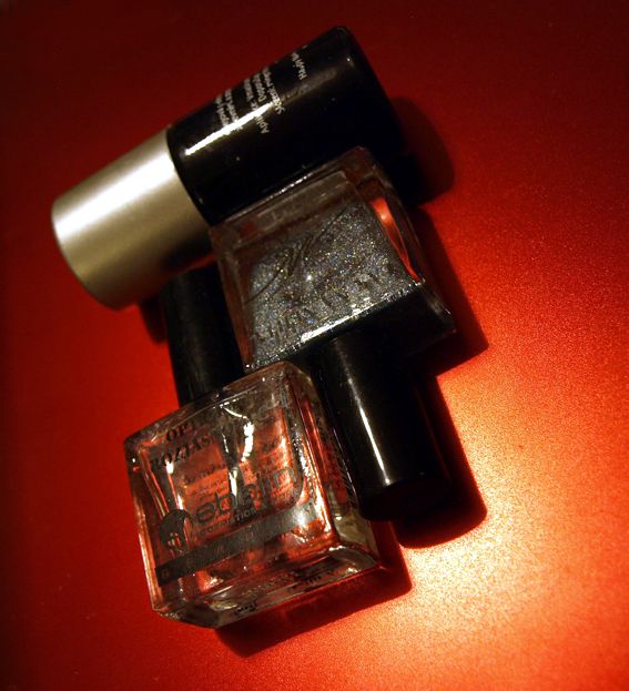 Zvlášnosti za pár kaček: vzadu vanilkový olejiček asi za stovku; má štěteček a okamžitě vylepšuje vzhled kůžičky. Vpravo je špičkový holograf, najdete ho v Globusu na věšáku mezi sponkami do vlasů a nálepkami na nehty; je české výroby, stojí asi 45,- korun, poměrně málo kryje, takže to chce hooodně vrstev, ale zase rychle schne; odměnou je dokonalý holografický efekt, kam se hrabe China Glaze (i když má hrubší zrnitost - nebo možná právě proto). Vlevo vepředu je UV top coat z DM, na věšáčku nad Sally Hansen; je lehce namodralý a při použití na laky studených barev jim dodává krásný námodralý nádech a lesk; na denním světle nehty úplně rozzáří (na diskotéce rozsvítí). 